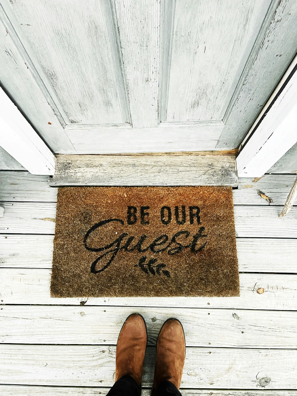 A doormat saying 'be our guest' at a short-term rental home