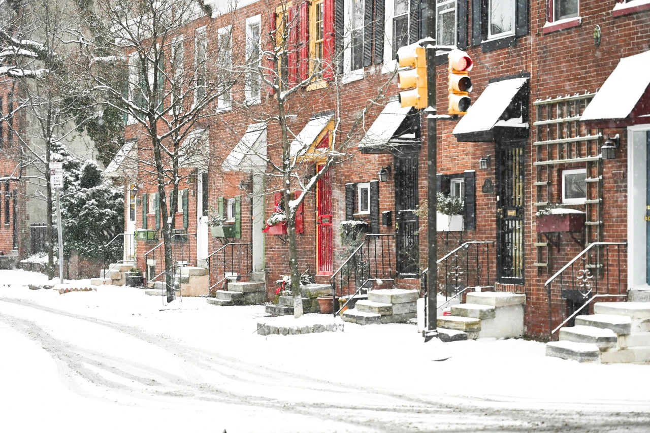 A row of townhouses with unshoveled snow on the sidewalk.