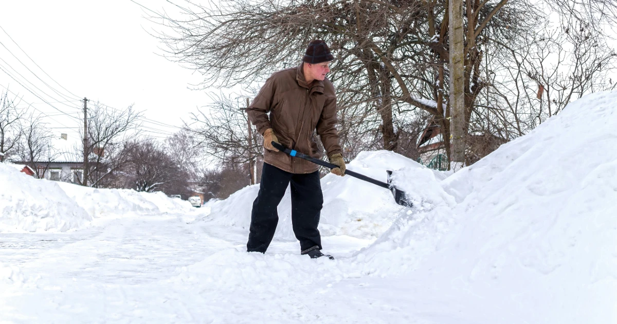 A man shovels snow on his sidewalk