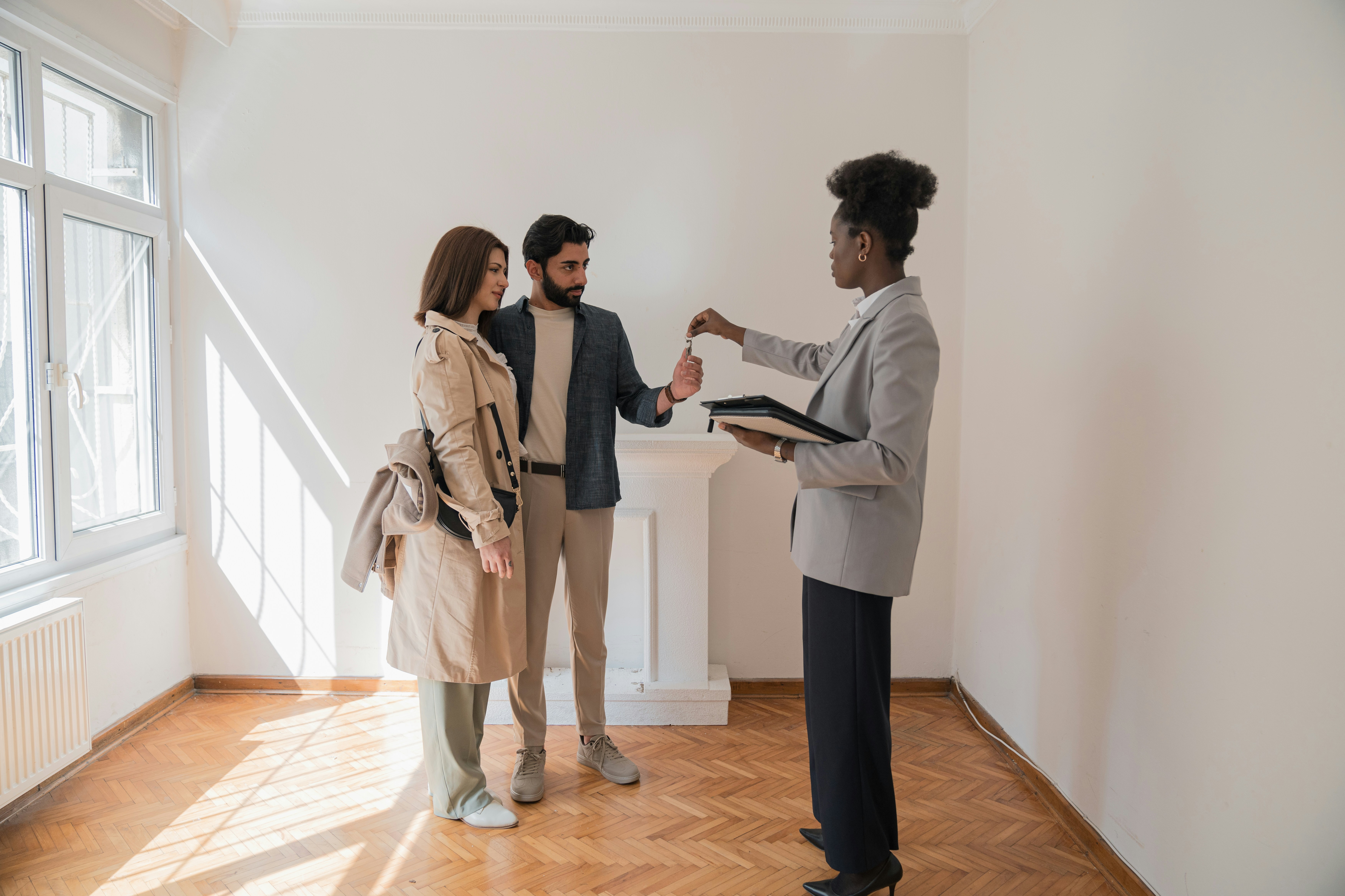 Property manager handing keys to a new tenant couple while reviewing paperwork on a clipboard