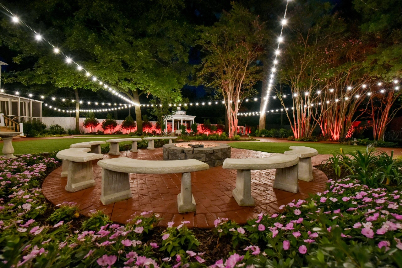 String-lit backyard with a stone fire pit and curved benches at the Tuscaloosa Airbnb