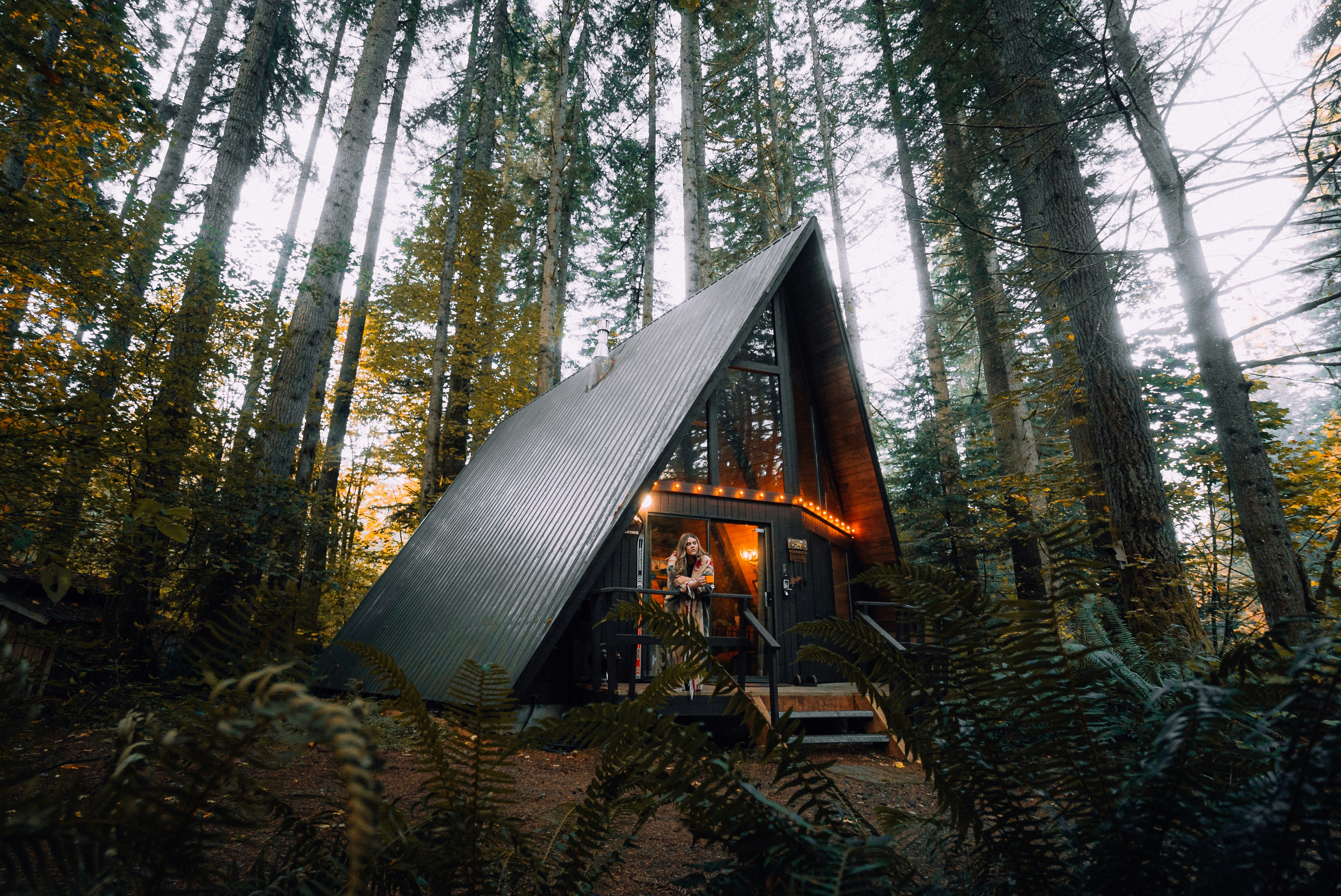 An A-frame cabin in a forest, available as a short-term rental