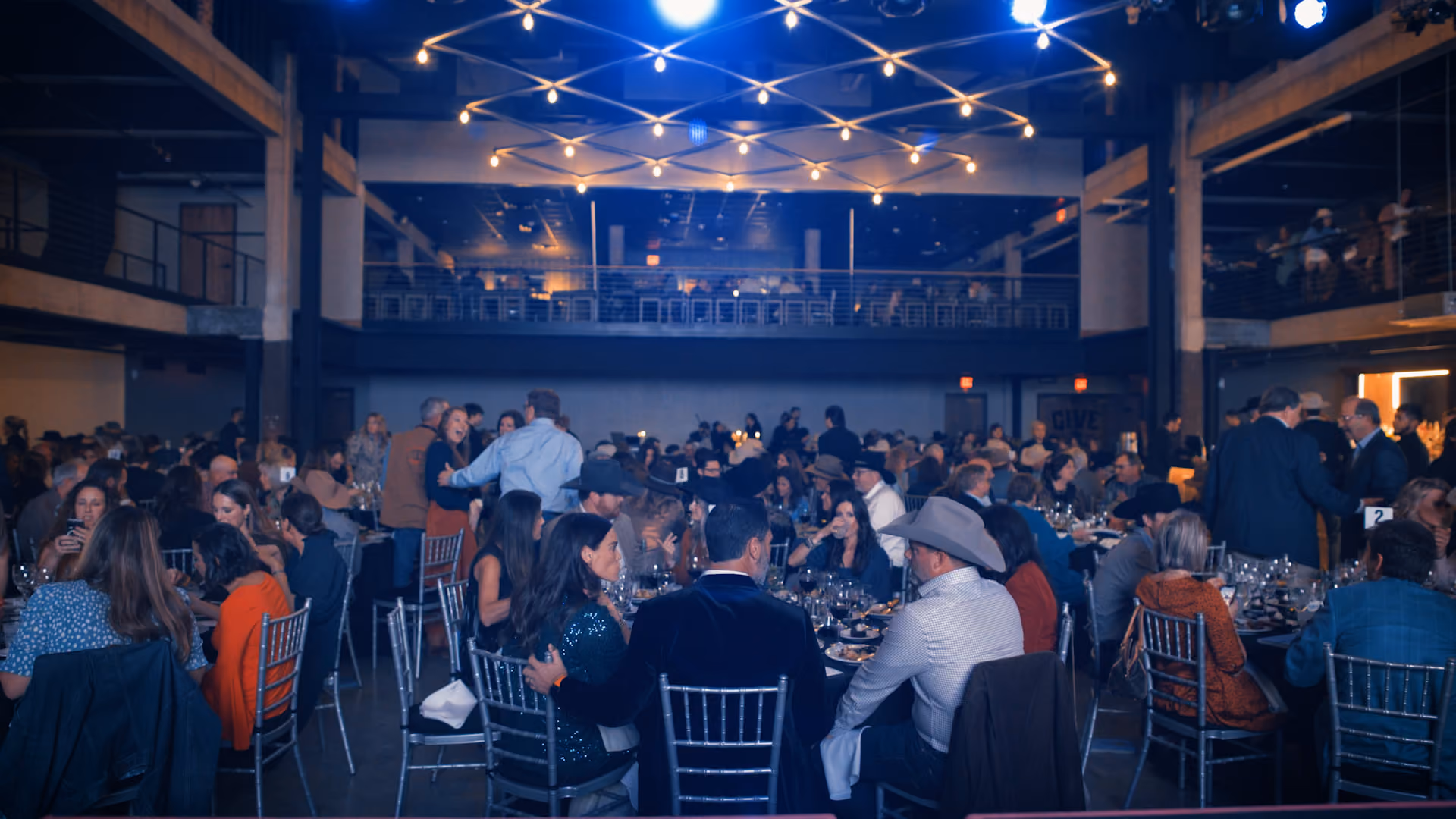 Guests seated at round tables under Tannahill's string-light canopy during a private event