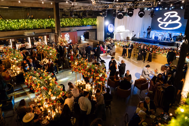 Wedding reception filling the music hall with tall floral centerpieces and a live band on stage