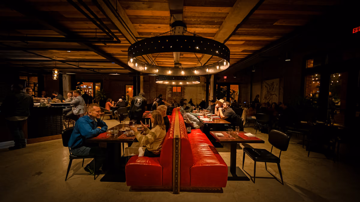 Red leather booths and communal tables under the chandelier at Love's BBQ & Oyster Bar