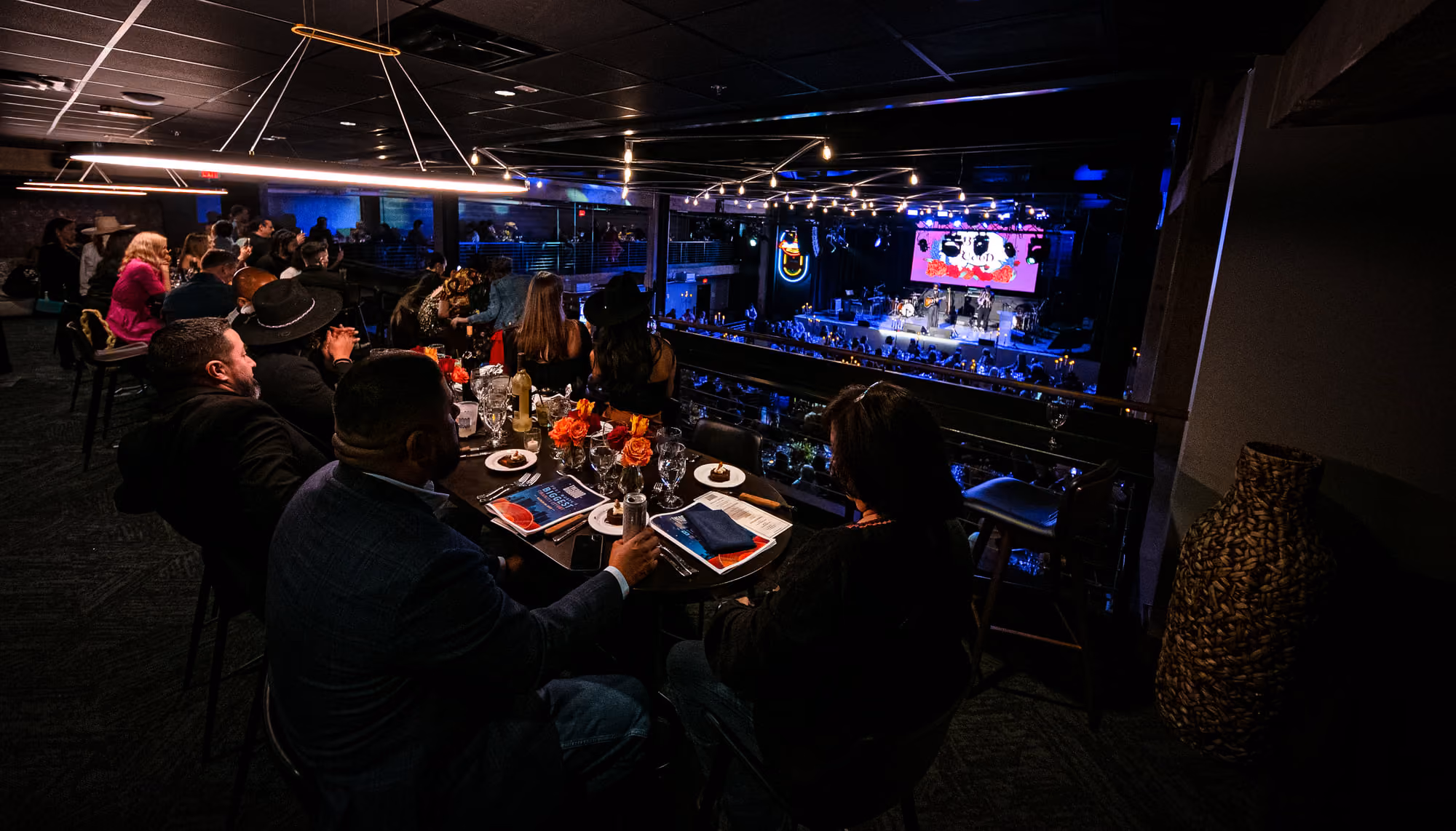 Guests dining on the mezzanine overlooking the lit stage in the music hall below