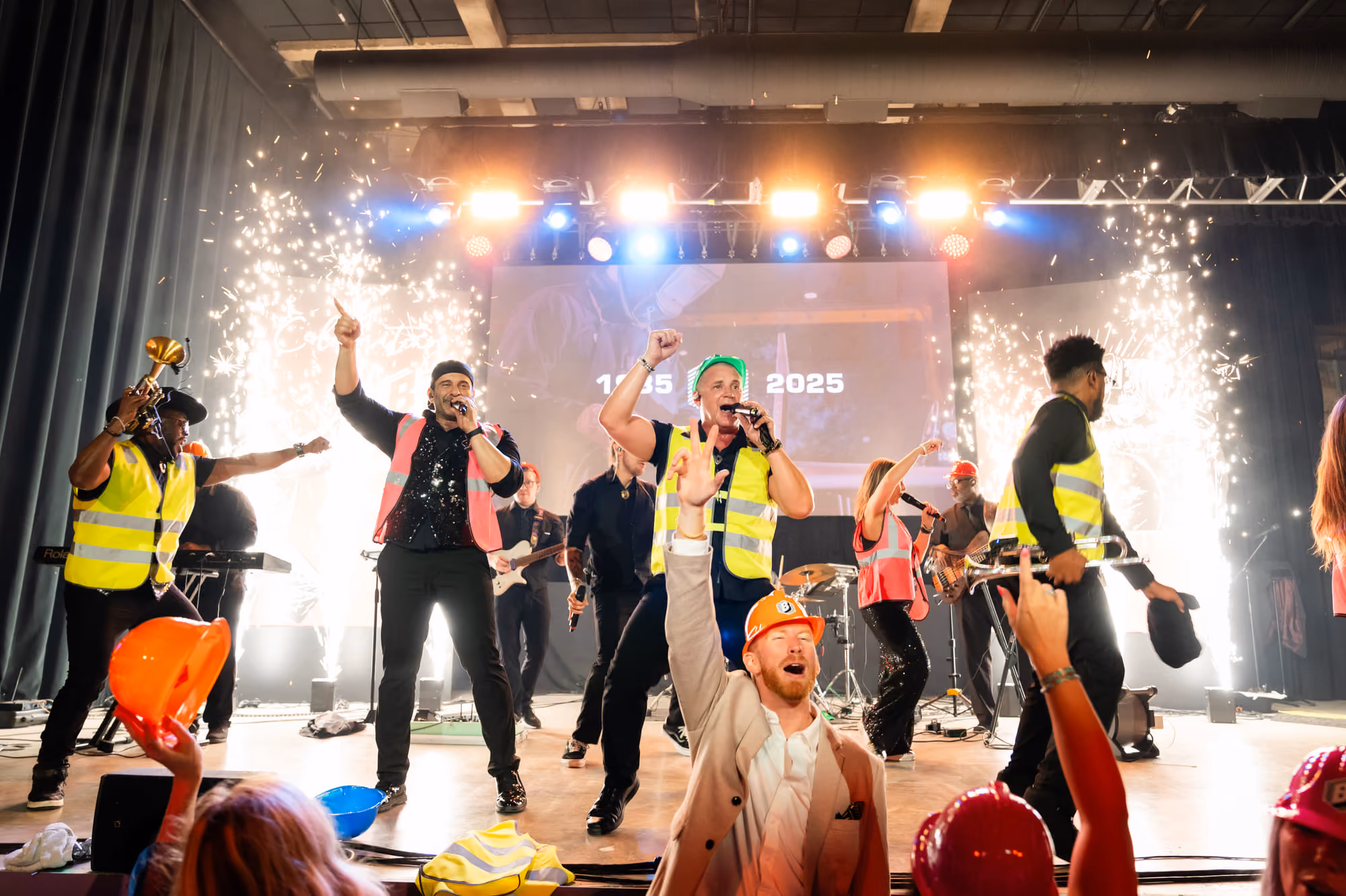 Band performing with stage pyrotechnics at a company 40th anniversary celebration