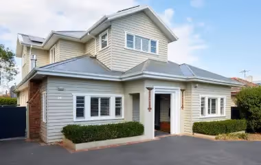 Two-storey extension on a weatherboard home with light grey cladding.