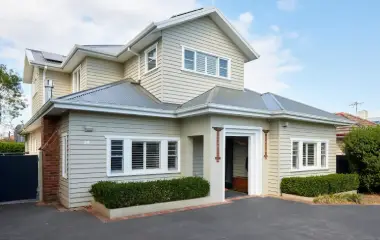Two-storey extension on a weatherboard home with light grey cladding.