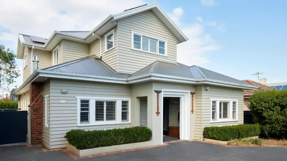 Two-storey extension on a weatherboard home with light grey cladding.