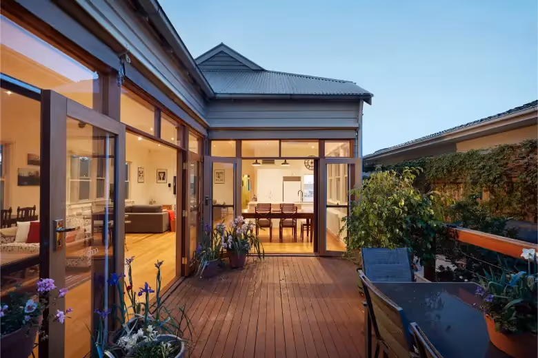 Modern home extension with timber deck, large glass doors, and open-plan kitchen and living area.