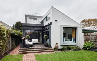 Contemporary two-storey home extension with large windows, timber deck, and landscaped backyard.