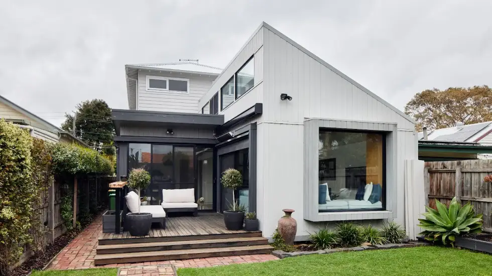 Contemporary two-storey home extension with large windows, timber deck, and landscaped backyard.