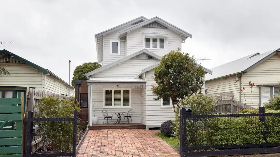 Two-storey weatherboard home extension with white cladding.