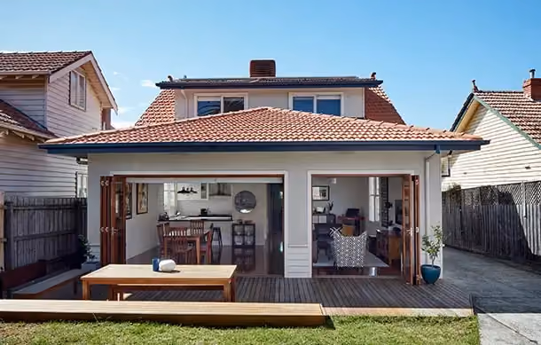 Rear house extension with large sliding doors connecting indoor living space to a timber deck.