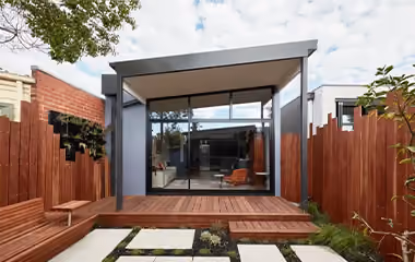 Modern rear home extension with timber deck, landscaped courtyard and floor-to-ceiling glass doors.