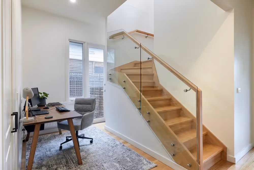Contemporary home extension featuring a timber staircase with glass balustrade and a home office nook.
