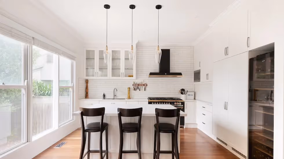 Modern white kitchen renovation with a central island, timber flooring and contemporary cabinetry.