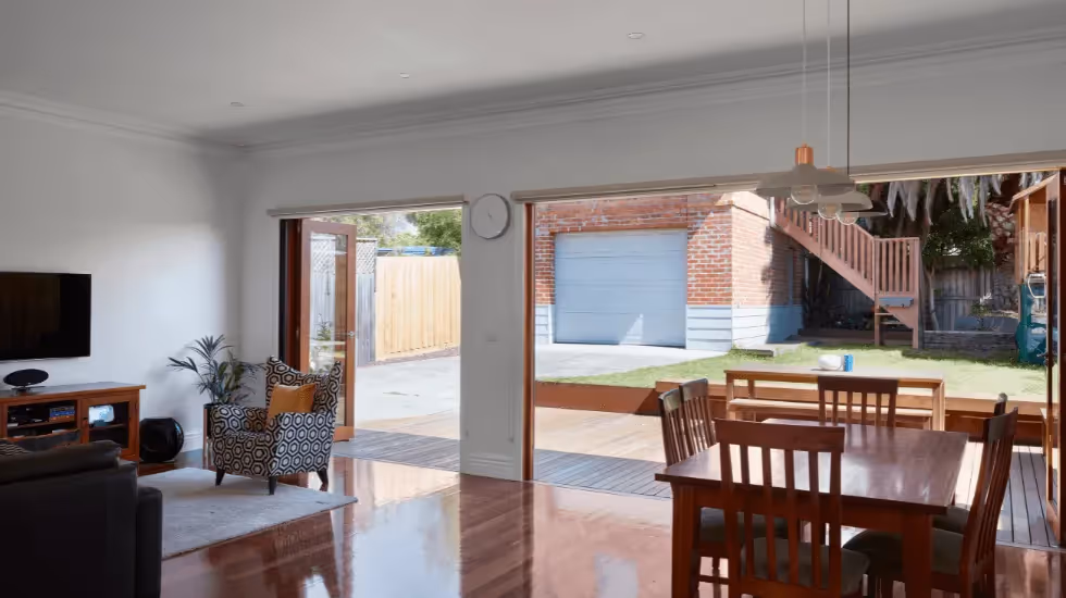 Open-plan living and dining area created through a modern home renovation overlooking the backyard.