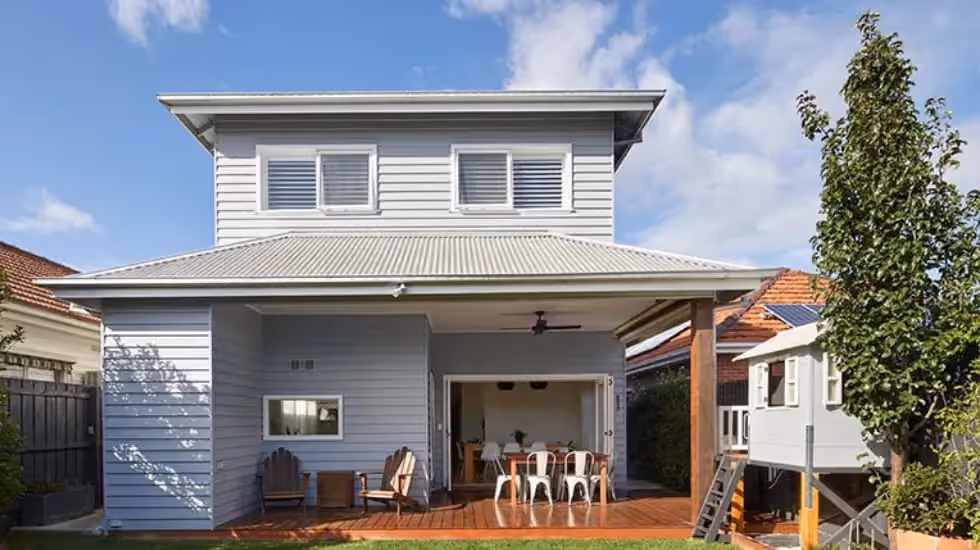 Rear view of a completed two-storey home extension with an outdoor entertaining area and covered deck.
