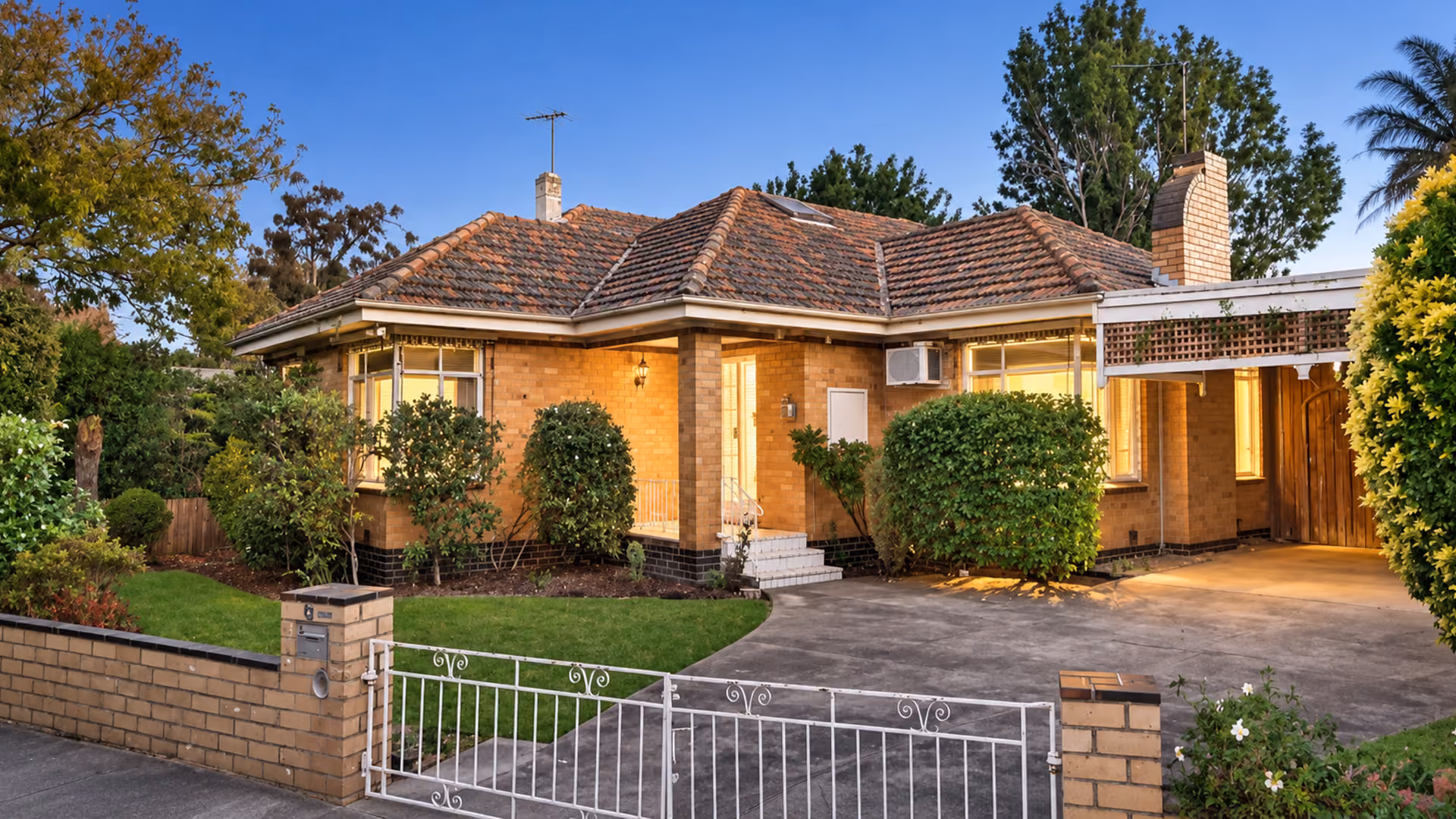 Well-maintained 1950s cream brick house with established front garden and driveway.