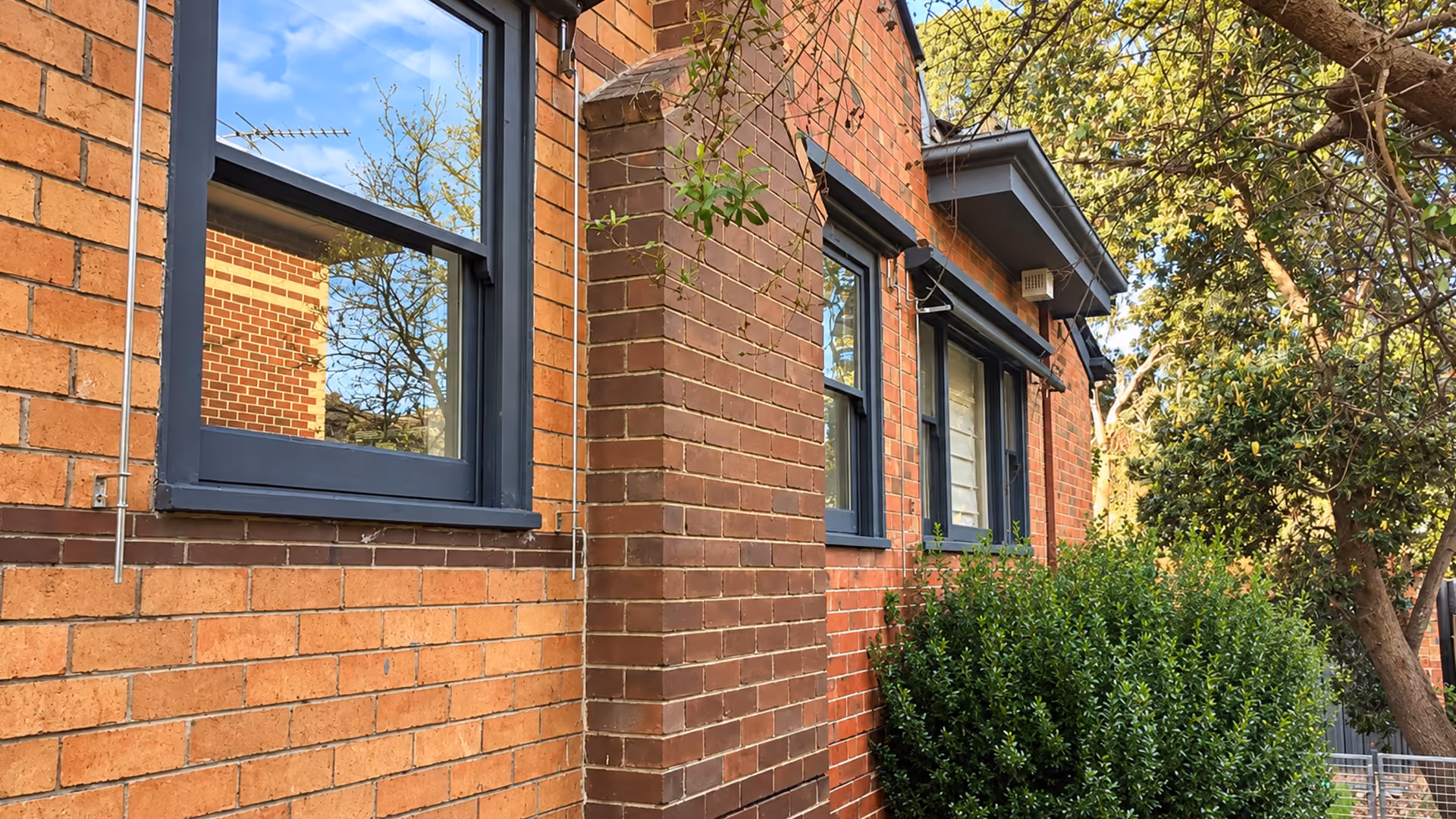 Close-up of original cream brickwork and restored window frames on a renovated home.