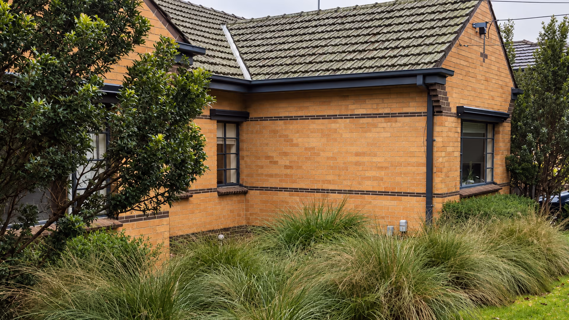 Side view of a classic cream brick house with original brickwork and landscaped garden.