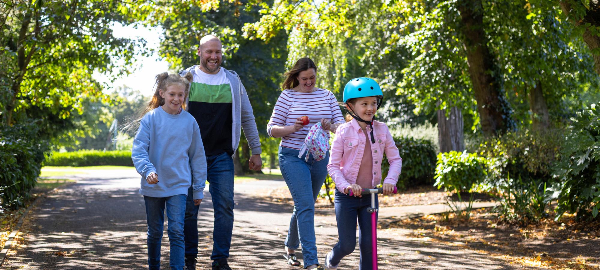 Parents and their children walking and scooting.