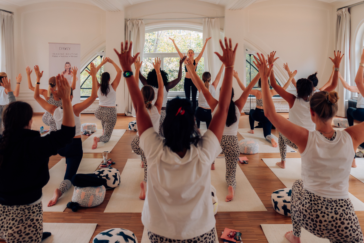 Gruppe bei einer gemeinsamen Yoga-Übung mit erhobenen Armen.