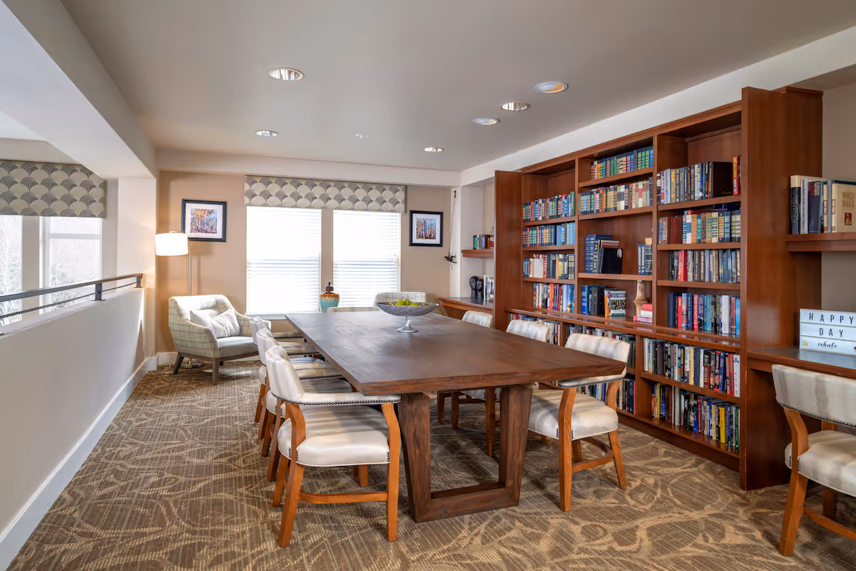 2 Bedroom Senior Apartments in Federal Way, WA | Federal Way | Library with Carpeted Flooring, Bookshelves, Conference Table and Chairs, Armchairs, and Large Window