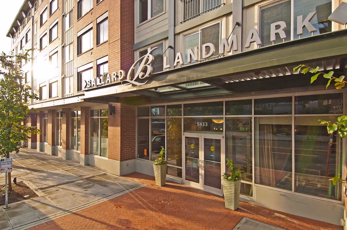 Retirement Homes in North Seattle, WA - Ballard Landmark - Exterior View of Property with Signage, Potted Plants, and Brick Entryway.