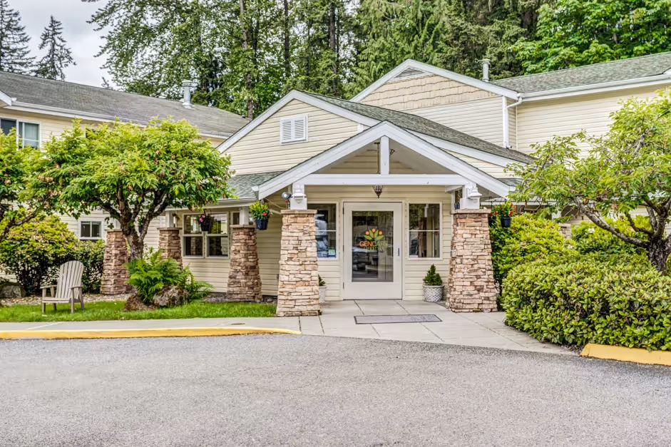 Two-Bedroom Senior Apartments in Granite Falls, WA - The Village at Granite Falls - Leasing Office with Paved Walkway, Lush Landscaping, and Brick Pillars.