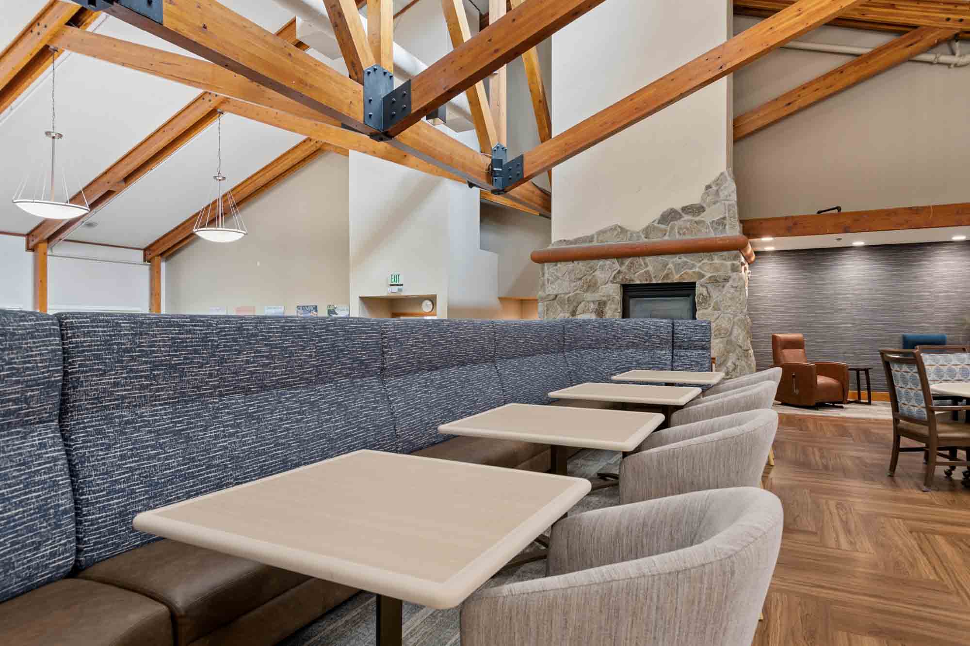 One-Bedroom Cottage Apartments in Renton, WA - GenCare Lifestyle Renton at The Lodge at Eagle Ridge - Apartment Kitchen With Wood Cabinets, Breakfast Bar, Open Living Area, And Large Window.