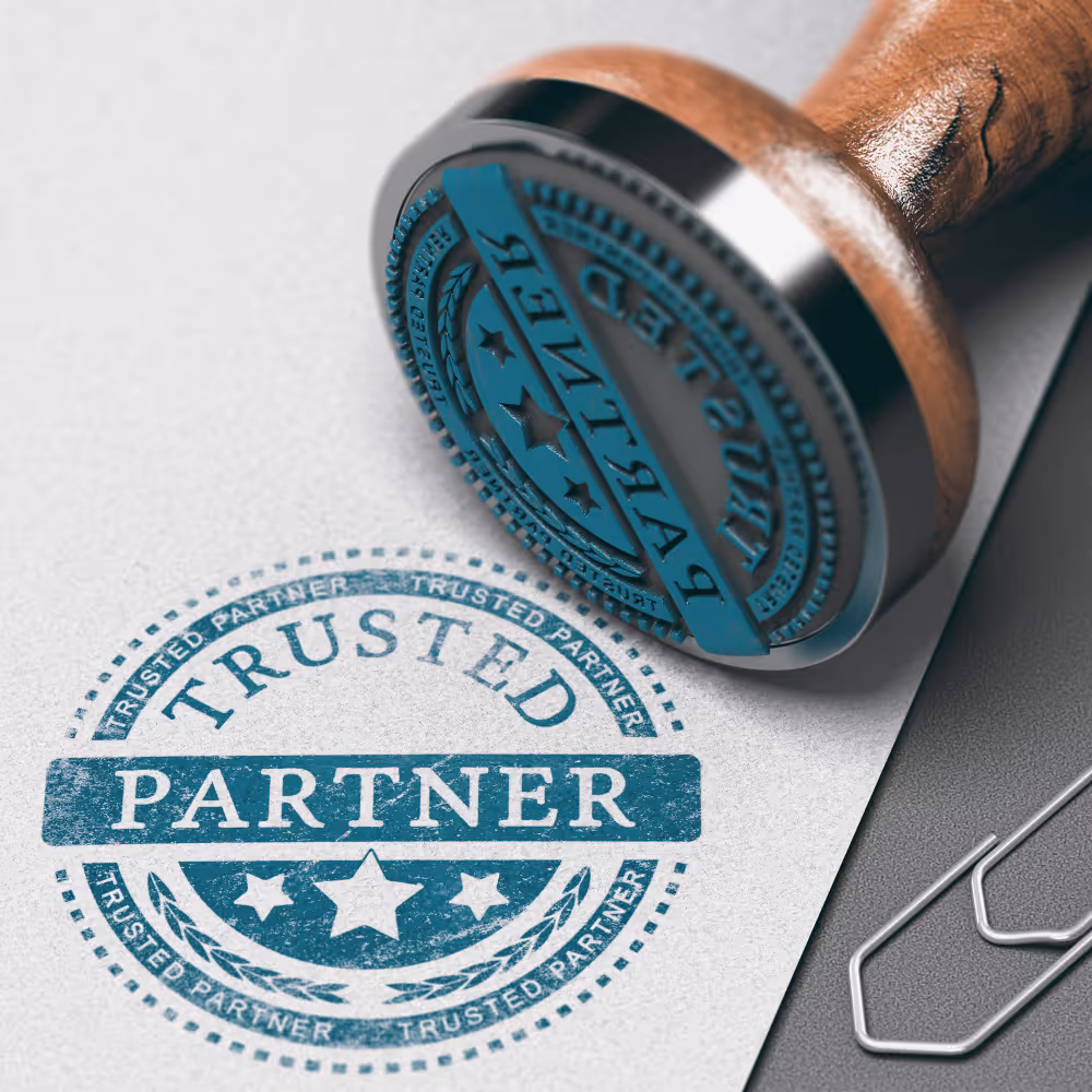 Close-up of a wooden-handled rubber stamp with the words 'Trusted Partner' stamped on white paper.