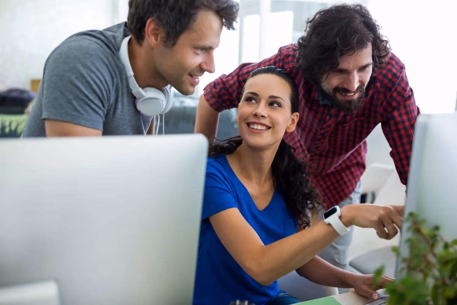 Three individuals attentively observing a computer screen together in a collaborative setting.