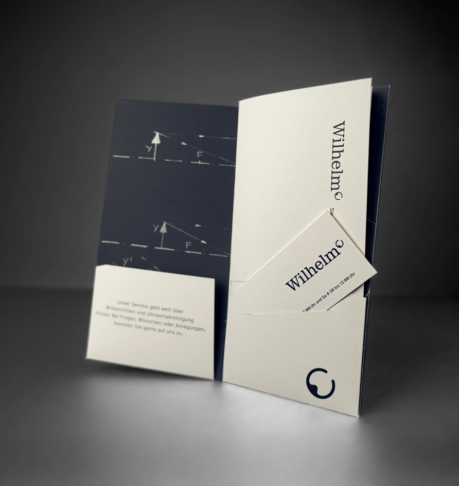 Eine offene Präsentationsmappe mit minimalistischem Design. Auf der linken Seite sind Schemata zu sehen, in der rechten Tasche befindet sich eine Visitenkarte. Der Ton ist professionell und elegant.