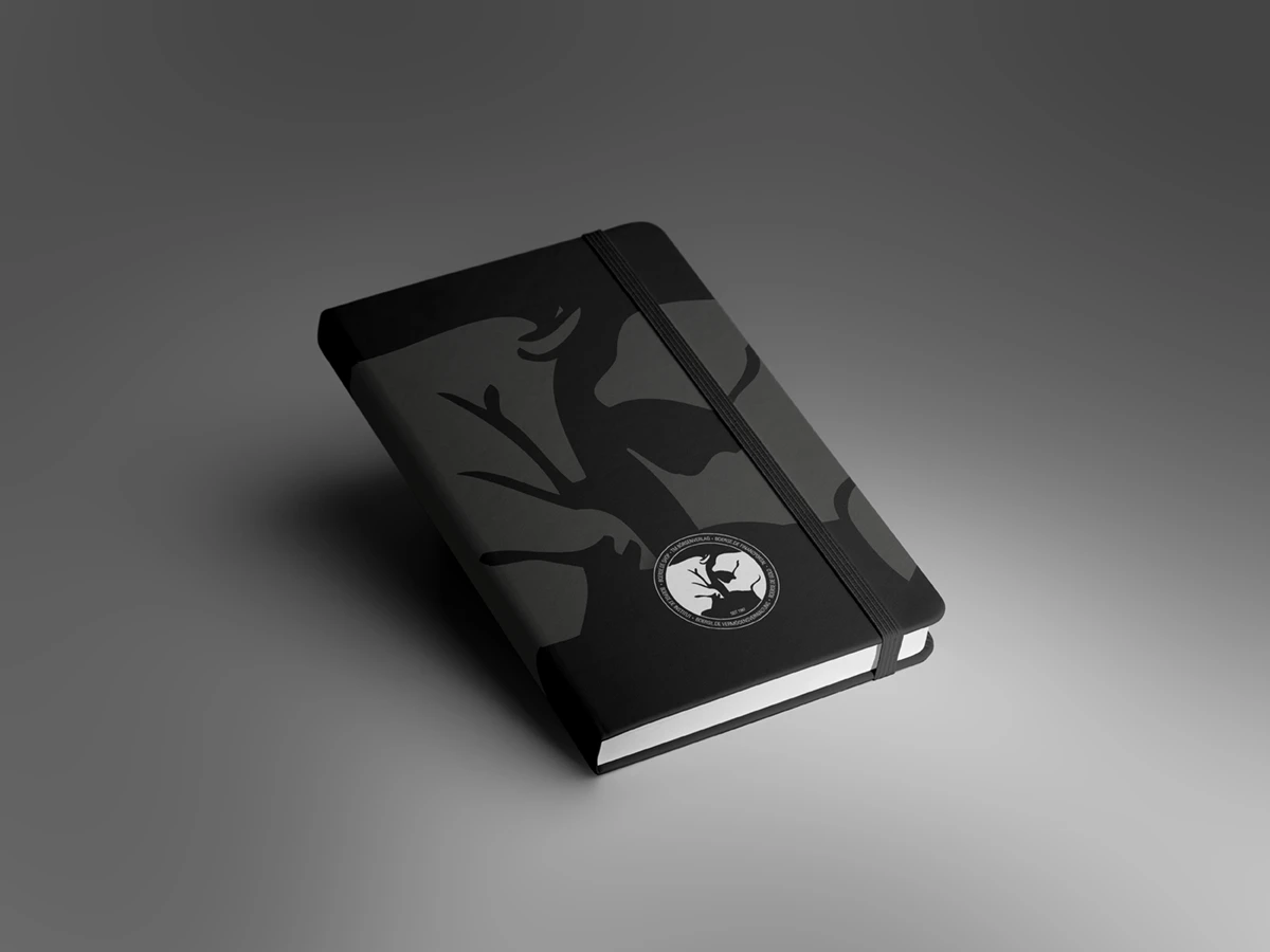 Ein elegantes, schwarzes Notizbuch mit Wasserzeichen des Börsenverlages (Bulle und Bär) und Gummiband. Auf dem Cover befindet sich ein kreisförmiges Logo mit Bulle und Bär in weiß