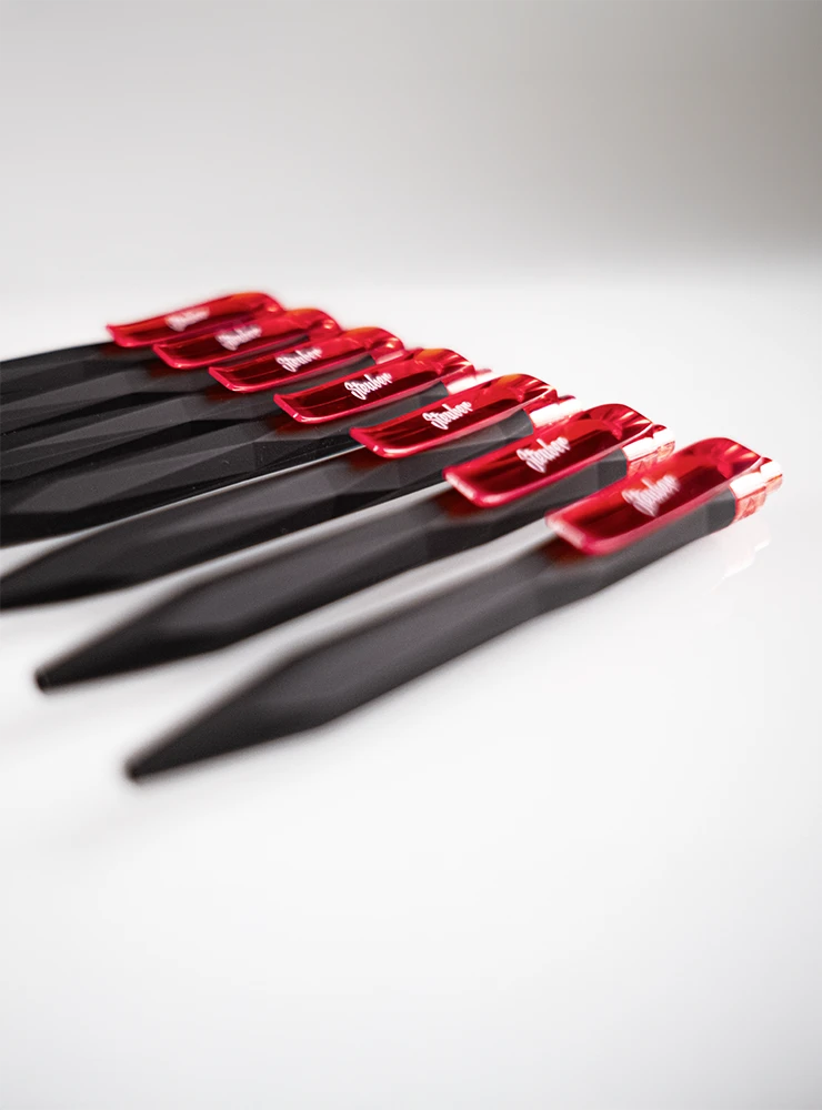 Sechs schwarze Kugelschreiber mit roten Clips, die in einer Reihe angeordnet sind. Auf jedem Clip steht 'Steuber'.