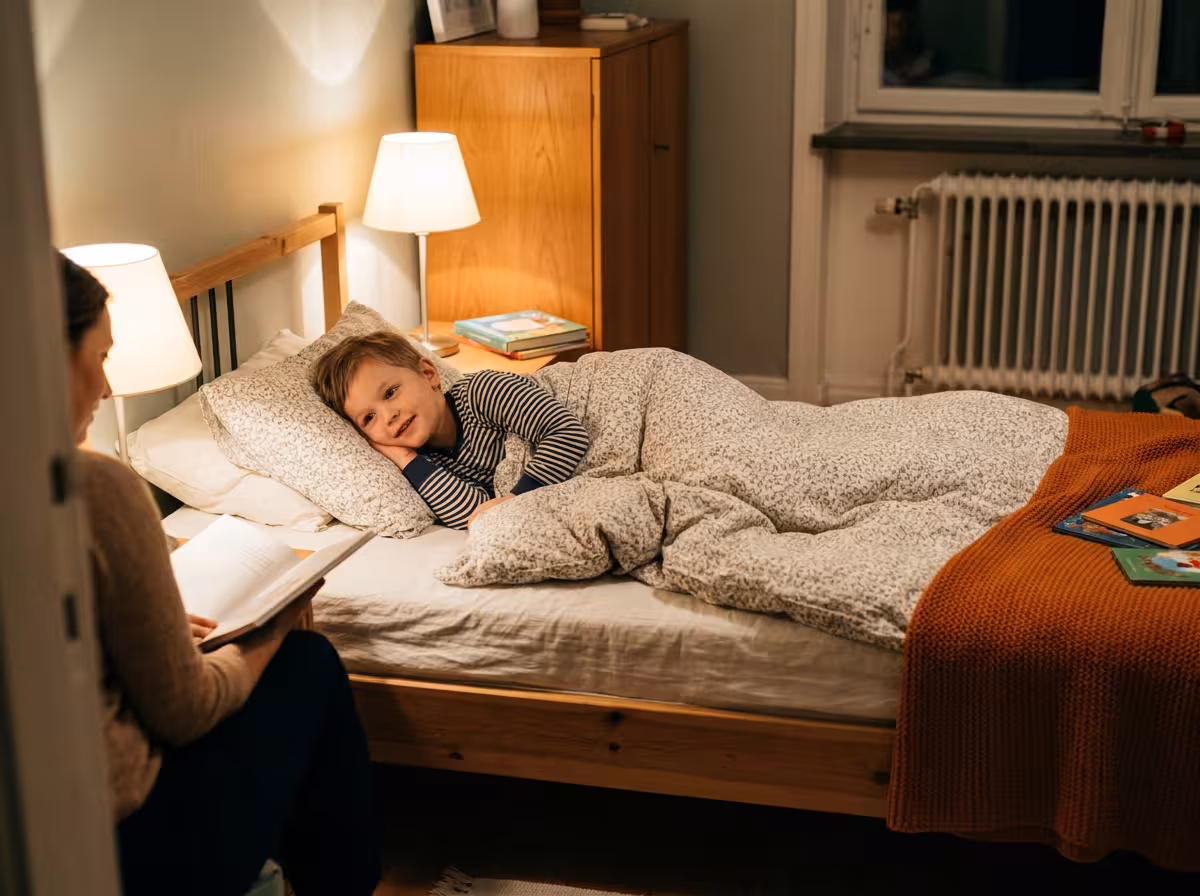 Ett barn i pyjamas lyssnar på en godnattsaga i sängen