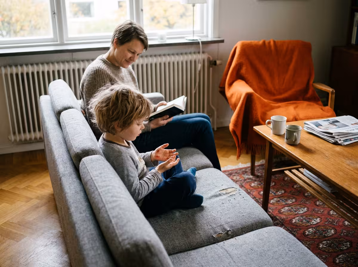 Barn med små blåsor på handen sitter i soffan med en förälder under hösten