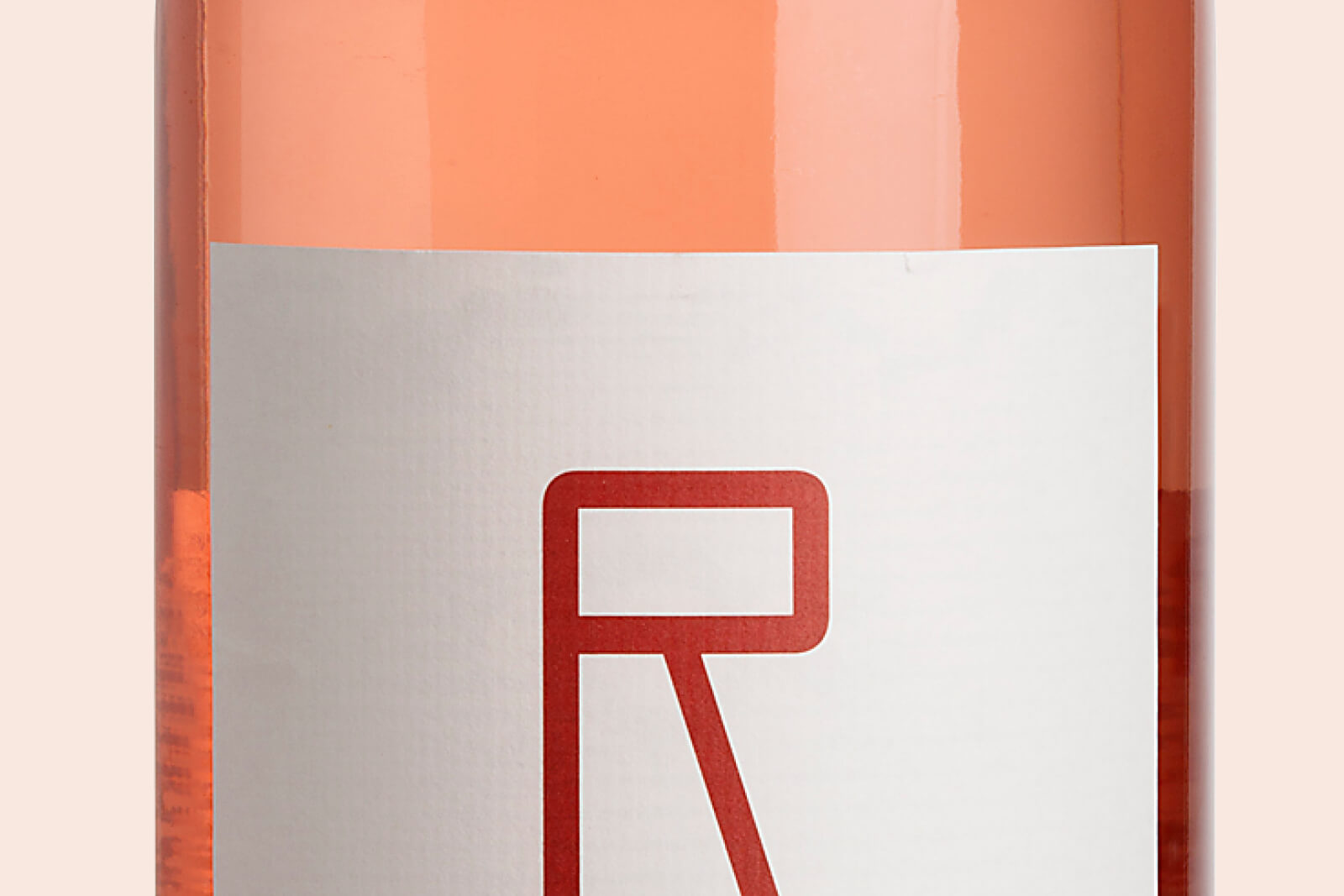 Flasche mit roséfarbenem Inhalt und weißem Etikett, darauf ein großes rotes stilisiertes R.