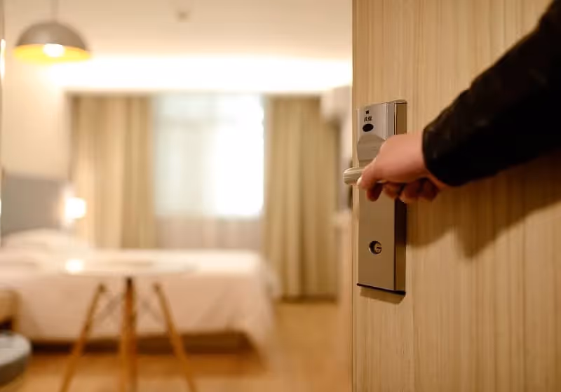 main ouvrant une porte donnant sur une chambre d'hôtel