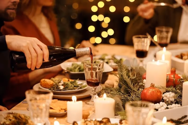 personne se servant un verre de vin pendant le repas de Noël