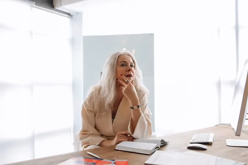 femme blonde qui réfléchit dans un bureau en tenant son menton