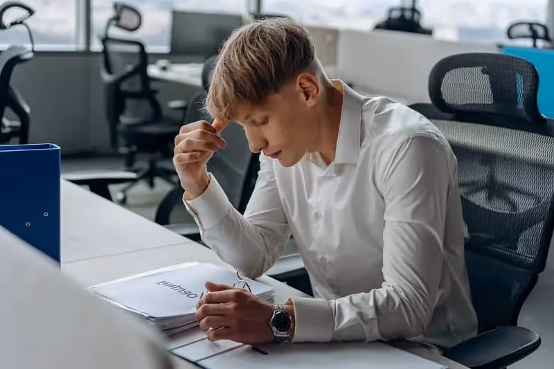 jeune homme qui réfléchit longuement sur un dossier au bureau