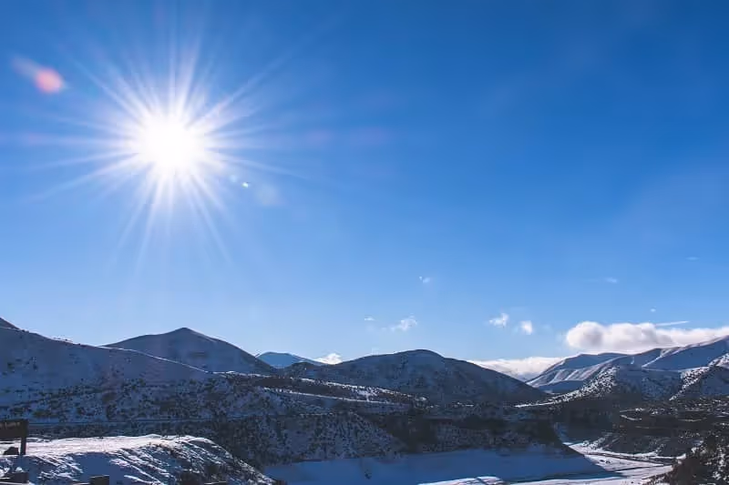 Montagnes enneigées pendant l'hiver avec un soleil très fort et un ciel bleu