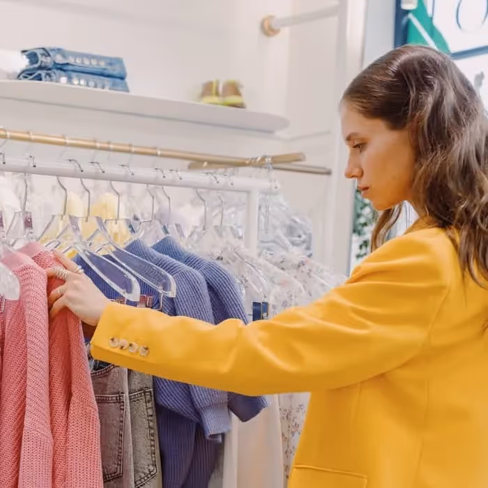 femme habillée en jaune qui cherche un vêtement en magasin