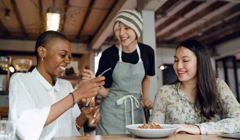 Trois femmes souriant devant un plat