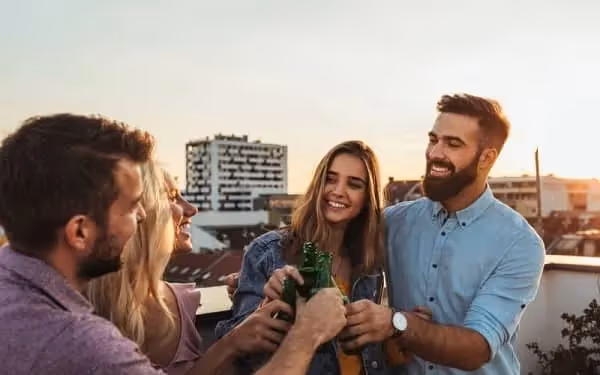Quatre amis qui boivent une bière sur la terrasse d'un toit pendant le coucher du soleil