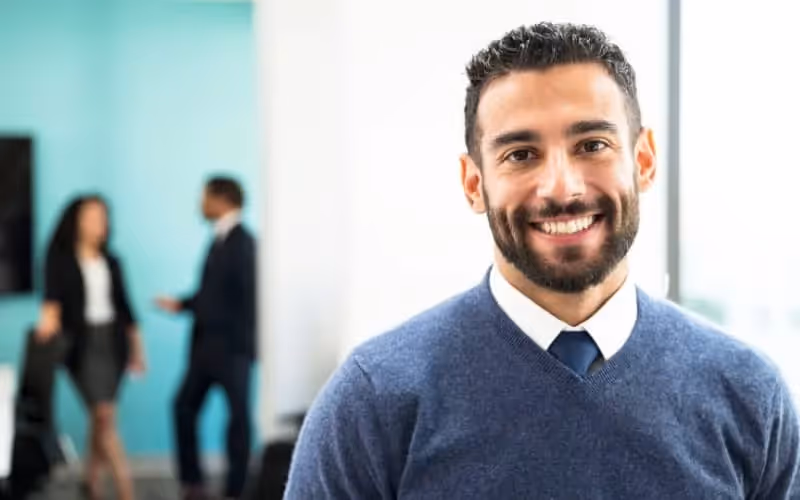 Homme souriant qui est auto entrepreneur face à la caméra